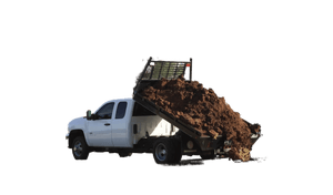 A white dump truck with a PIERCE Light Duty Flat Bed Dump Kit and a 12 Volt hydraulic pump unloads dirt onto a grassy field, trees in the background.