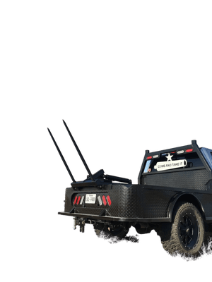 A PIERCE Truck Bed Gooseneck Hay Bale Mover with two large spikes is parked in a field under a clear blue sky.
