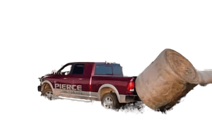 A red pickup equipped with the PIERCE Truck Bed Gooseneck Hay Bale Mover hauls a large round hay bale in a field at sunset.