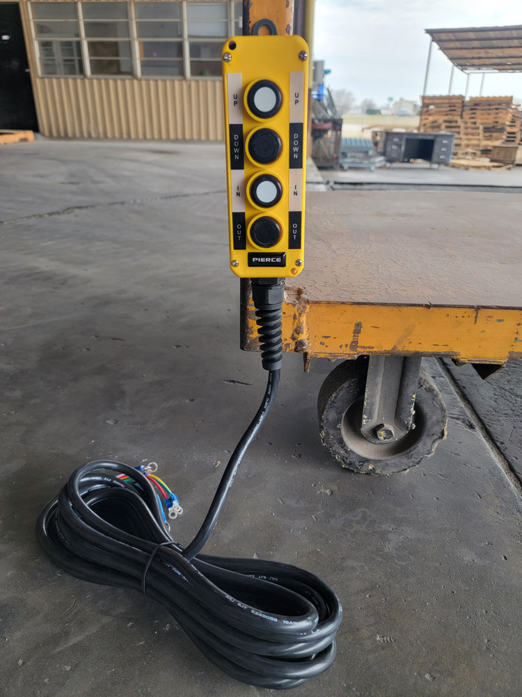 A PIERCE Universal Momentary Pendant Control - 4 Button - 20ft Cord, complete with magnets, is strategically positioned on the warehouse floor near a trolley.