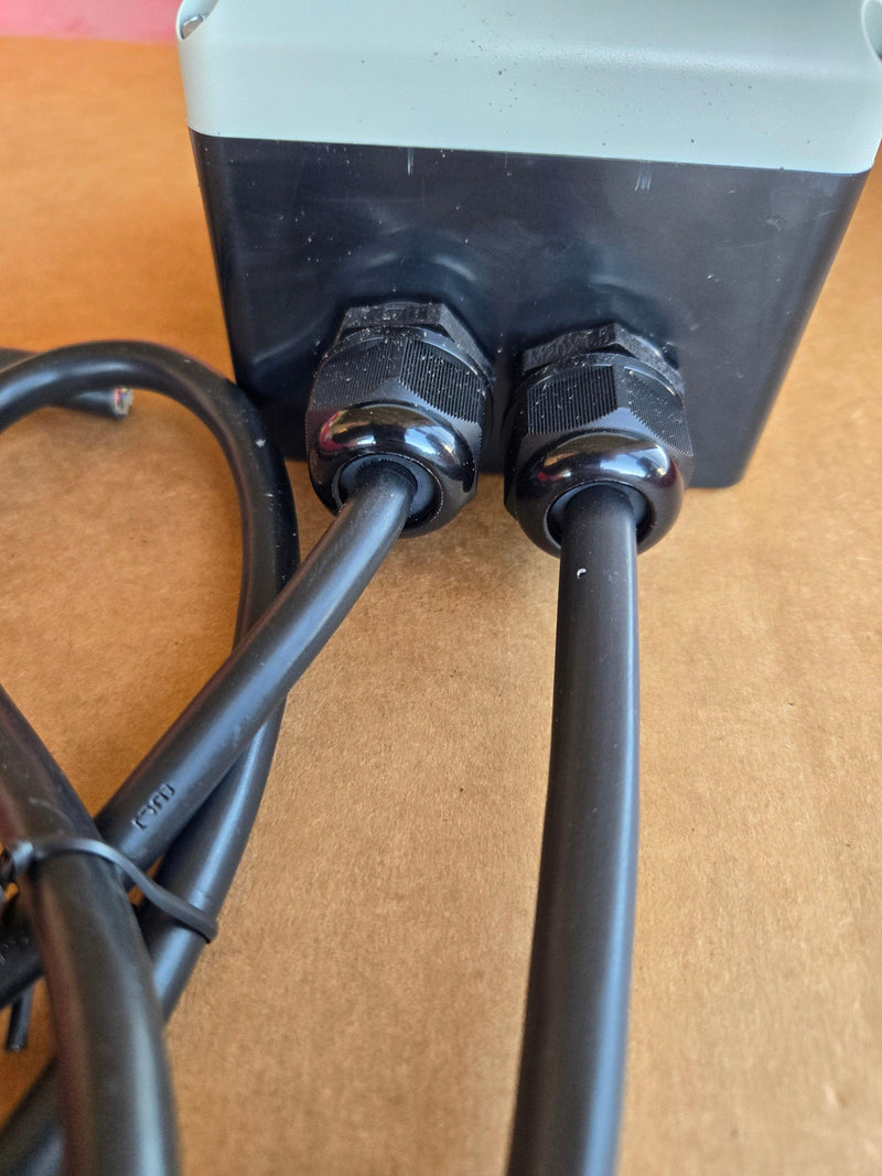 Two black cables connect to a black and gray IP65 thermoplastic PIERCE 654 Series Wired Control for 110V single-phase winch, resting on a brown surface.