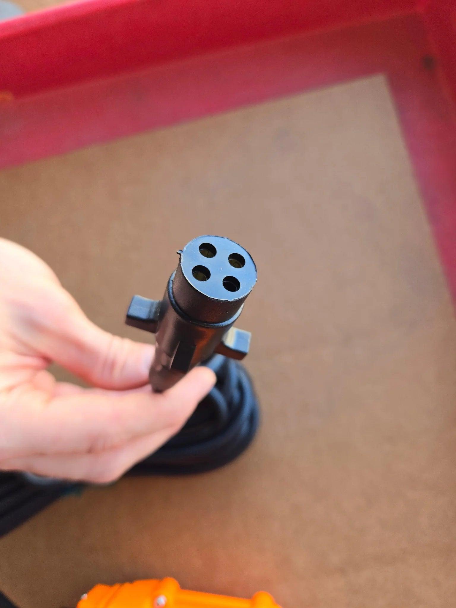 A hand holds the Asetek PIERCE 2 function Momentary Hard-Wired Control Pendant with a 15 ft. cord and 4 prong vulcanized plug above a brown surface.