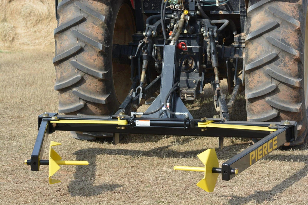 A tractor equipped with the Internal - Pierce Assembly Team 3-Point Hay Bale Unroller is used for rolling and laying irrigation pipes across a dry field.