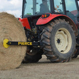 A red tractor equipped with the Internal - Pierce Assembly Team 3-Point Hay Bale Unroller moves a large round hay bale across the field.