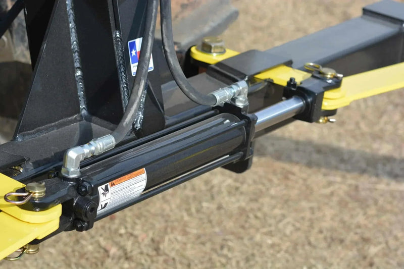 Close-up of a hydraulic cylinder on the Internal - Pierce Assembly Team 3-Point Hay Bale Unroller, a durable tractor attachment, shown outdoors on dry grass.