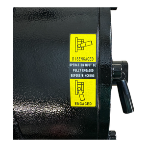 Close-up of the PIERCE 30,000 lb Hydraulic Recovery Winch with Long Drum and Manual Clutch displaying a yellow label that details Engaged and Disengaged instructions. The robust design includes a planetary gear system, ensuring efficient operation that effortlessly handles loads up to 30,000 lb.