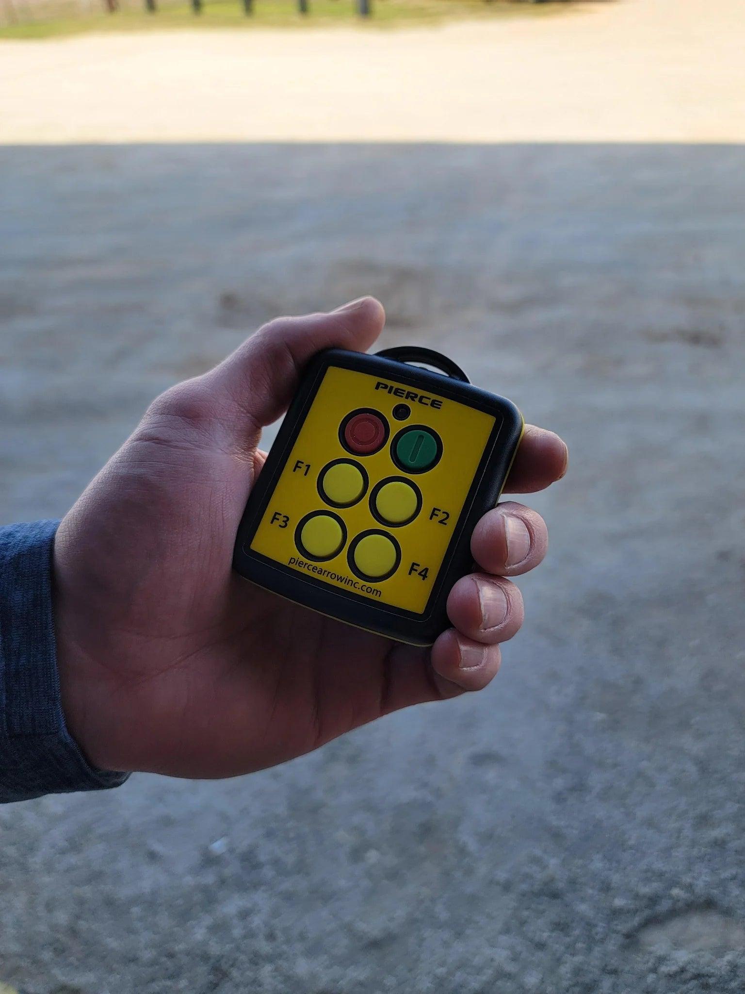 A hand holds a Lodar LTD 4 Function Wireless Remote Control System with labeled buttons outdoors.