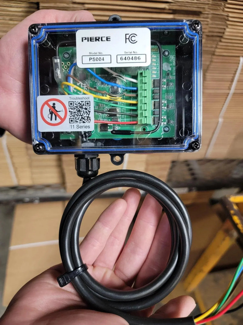 A person holding a Lodar LTD 4 Function Wireless Remote Control System | Roll-off Trailer Edition, featuring exposed wiring and a connected black cable, used for operating hydraulic pumps or remote-control systems on roll-off trailers.