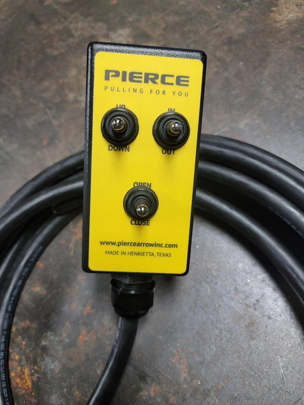 The PIERCE 6 Function Wrecker Remote is a yellow control with three switches—Down/Up, In/Out, and Open/Close. It features a black cable and is ideal for smooth operation of hydraulic power units or solenoid systems.
