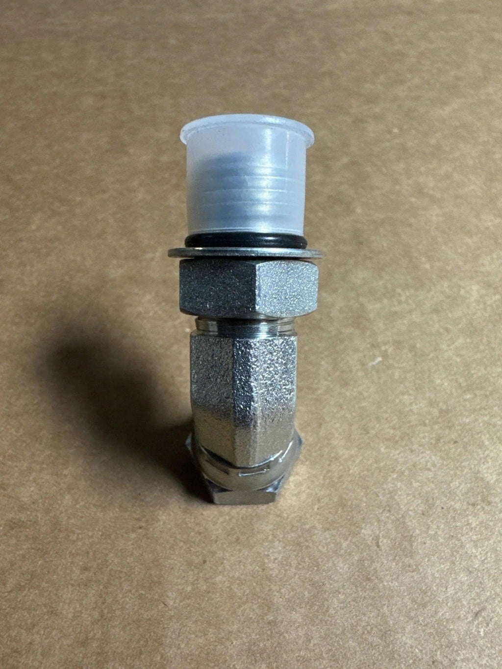 A PIERCE Hydraulics Fitting, Boss Thread Swivel (Male 9/16 in x Female 1/4 in, 45 Degrees) with a plastic cap is placed on a plain brown surface.