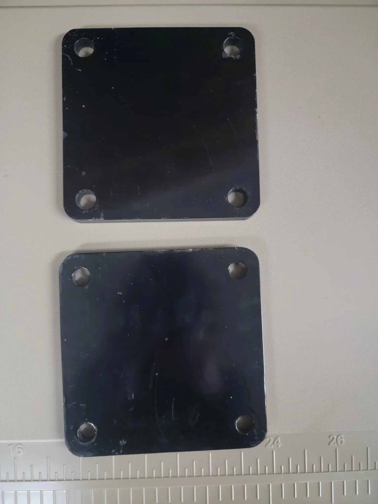 The PIERCE Bale Unroller Extension Set includes two square black metal plates with four corner holes—perfect for extending your unroller to handle 4-foot round hay bales.