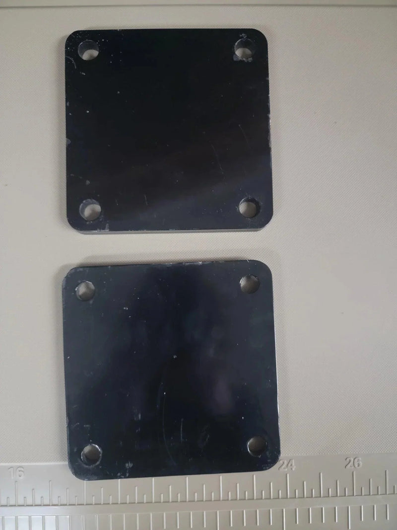 The PIERCE Bale Unroller Extension Set includes two square black metal plates with four corner holes—perfect for extending your unroller to handle 4-foot round hay bales.