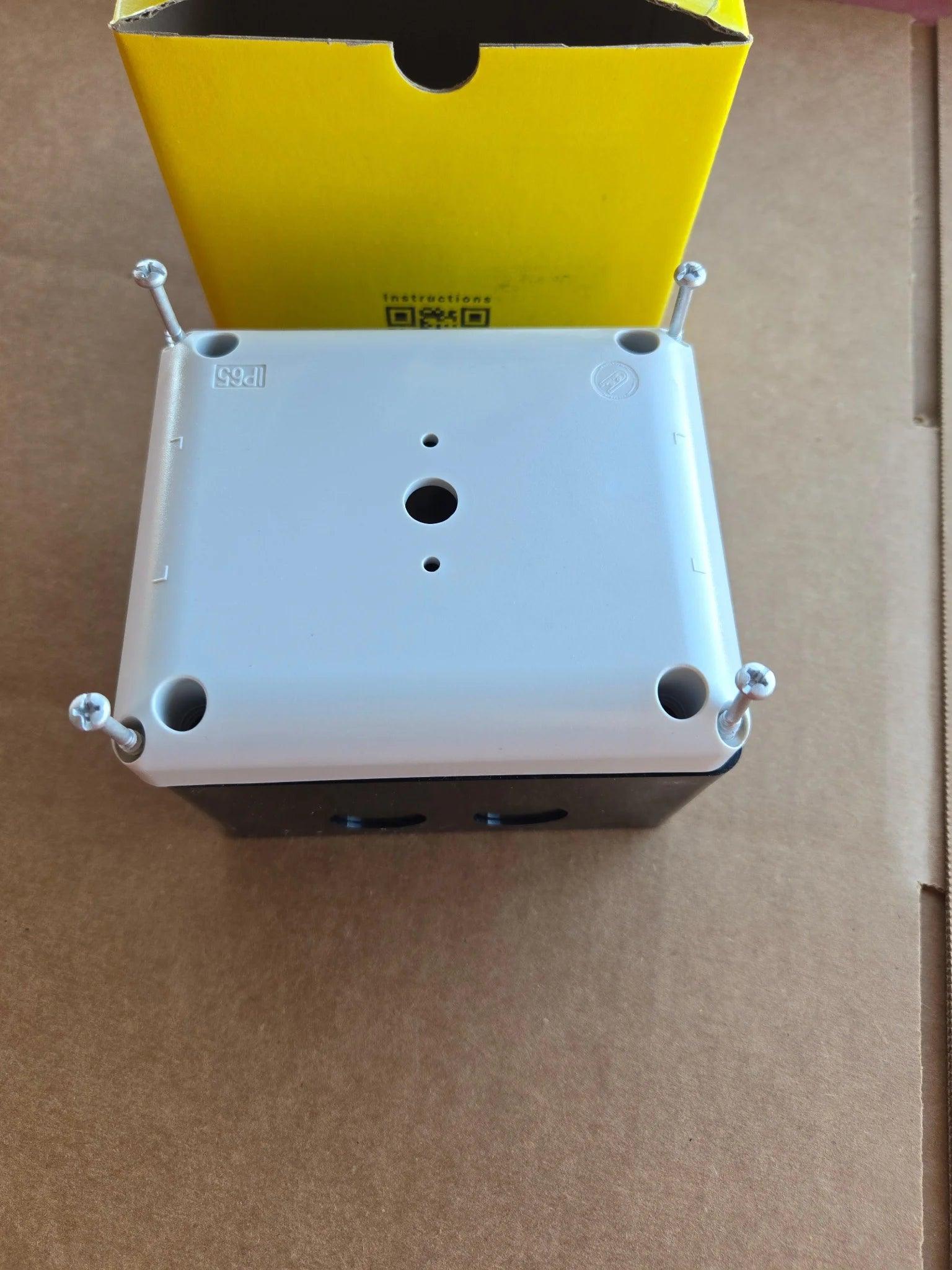 An ASI.Easy.com Control Box for 110V PIERCE 654 Series Single Phase Winch, housed in a gray IP65 enclosure with four screws, is placed in front of an open yellow box on a cardboard surface.