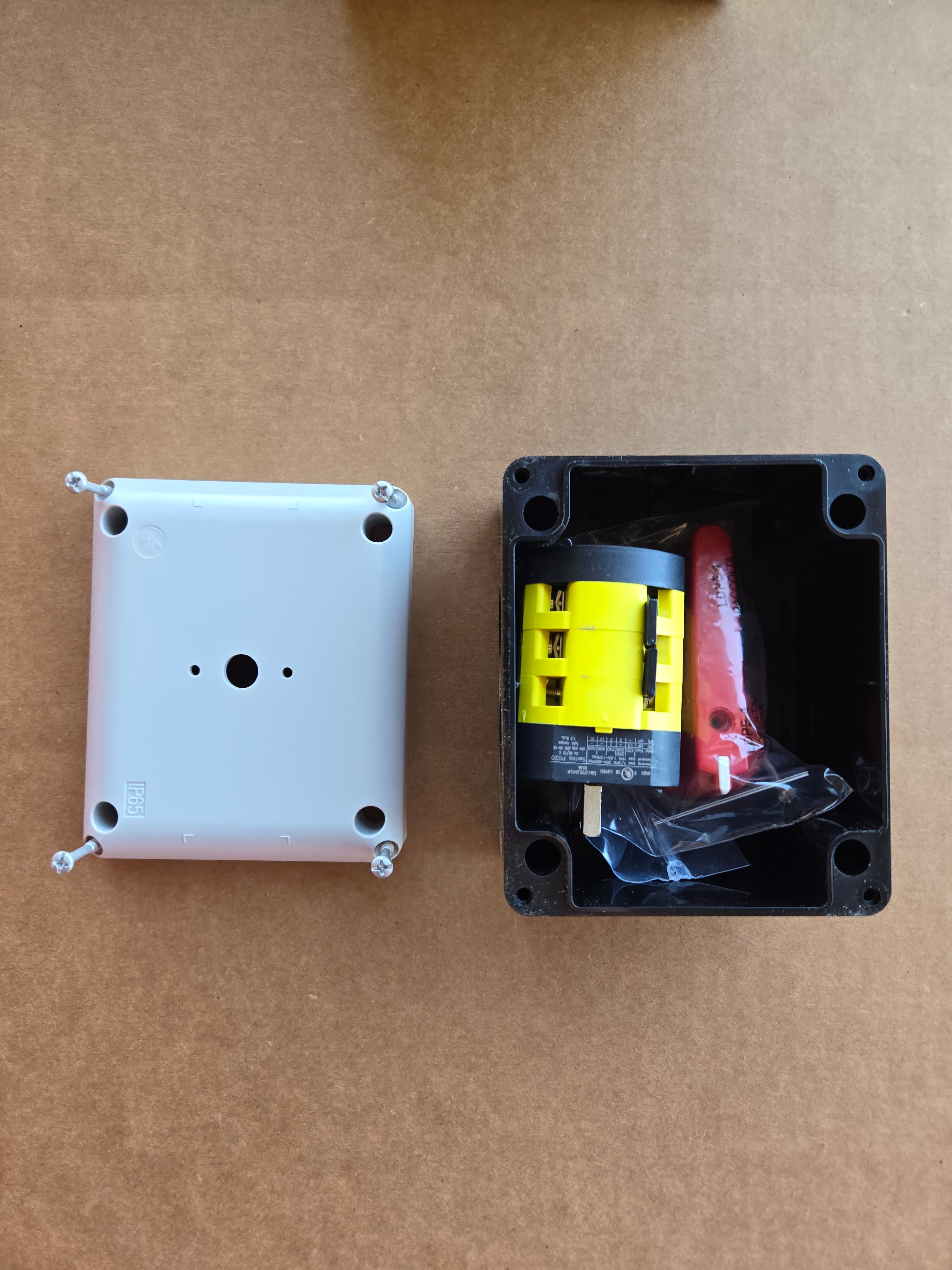 An open PIERCE Control Box for 110V PIERCE 654 Series Single Phase Winch sits next to a white cover on cardboard, commonly used in industrial settings.