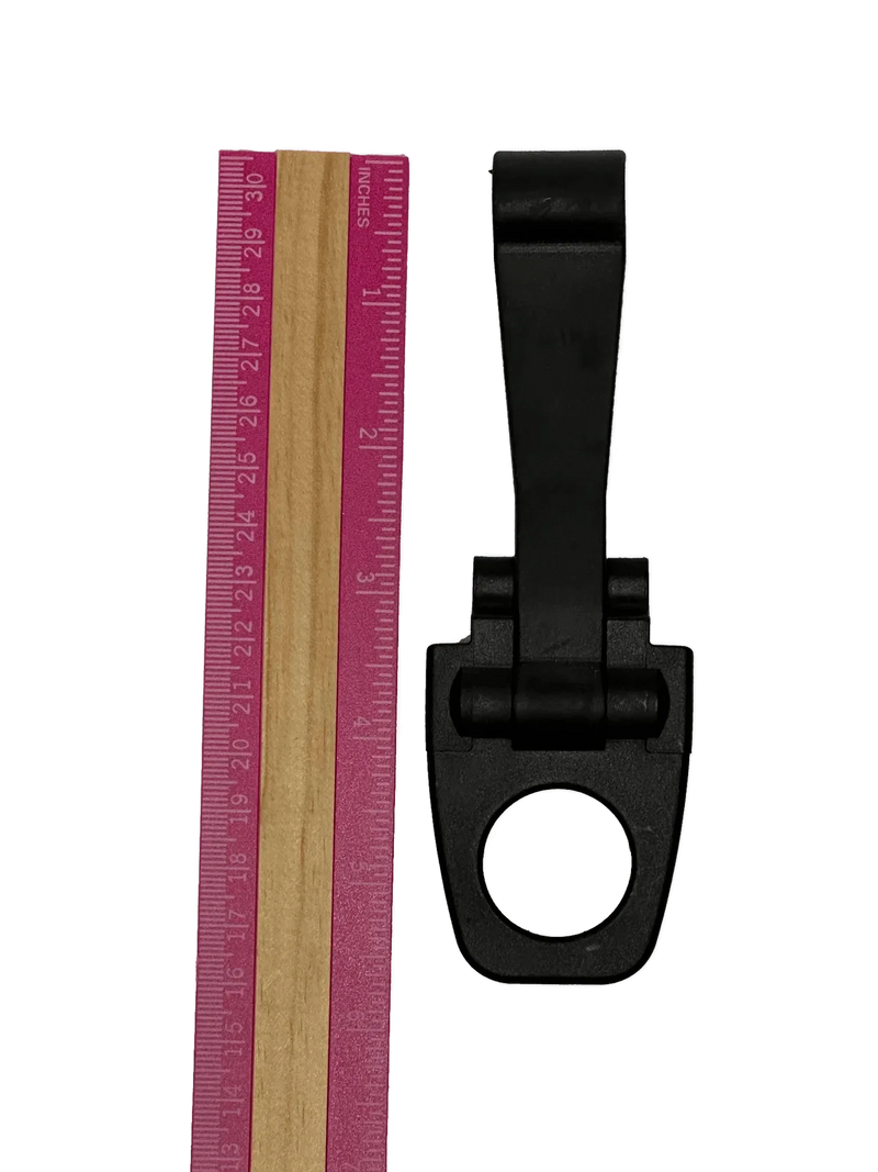 A PIERCE Coolers | Latch | Long | Version 2, black plastic clip with a circular opening, is shown beside a pink and wood ruler on a white background.