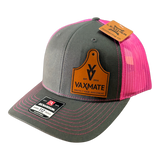 The PIERCE VAXMATE Trucker Hat with Leather Patch features a gray and pink design, a VAXMATE ear tag patch on the front, and comes with brand tags attached.