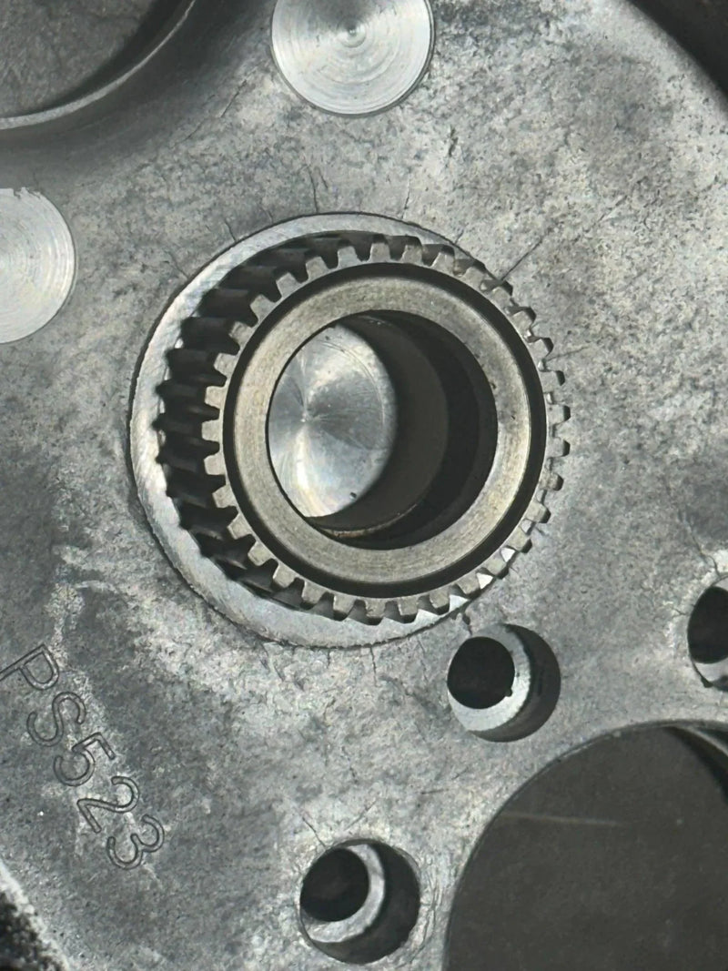 Close-up of a PIERCE Transfer Housing 654 Series (12,500 lbs) gear mechanism, featuring engraved markings and circular openings on its machined surface.