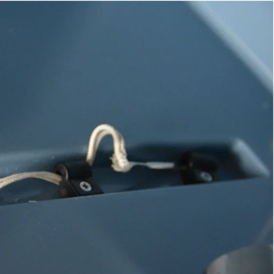 A close-up of a knotted white string attached to a dark blue VaxMate Vaccine Cooler by Ningbo Kuer Co., LTD CoolKayak, featuring metal fasteners for secure storage of vaccines and veterinary supplies.
