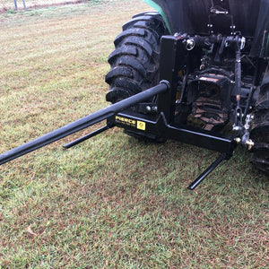 A PIERCE 3 Point Tractor Bale Spike with a black hitch attachment is set on the grassy field, perfect for handling round bales effortlessly.